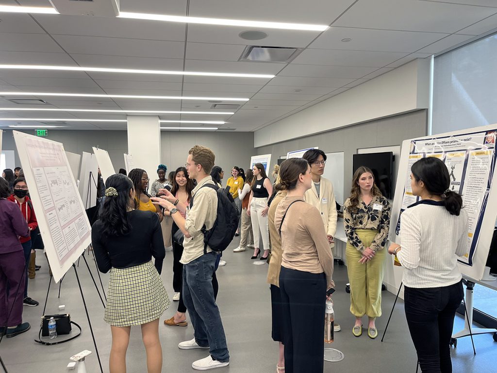 Students viewing and discussing research posters in a large room